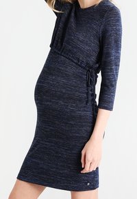 Marinblå passformad gravidklänning med trekvartsärmar, strukturerad stickad tyg, sidosammandragning och en bekväm silhuett.