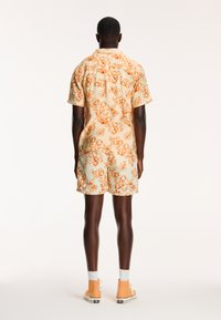 Korte mouwen bloemen shirt en bijpassende shorts in lichtbeige met oranje patronen, gemaakt van lichtgewicht stof, met een relaxte pasvorm.