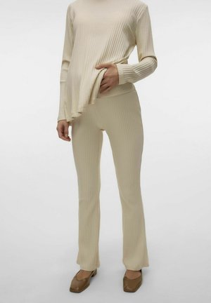 Bežový pruhovaný top s dlhým rukávom v kombinácii s rovnako pruhovanými nohavicami. Mäkká textúra, priliehavý strih a uvoľnená silueta. Hnedé topánky dopĺňajú outfit.