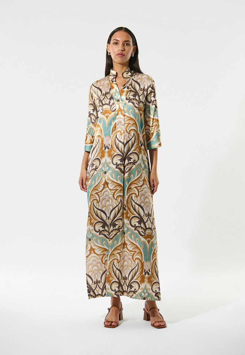 Robe longue à motifs avec un col et des manches trois-quarts. Présente des motifs floraux dans des tons de brun, turquoise et crème.