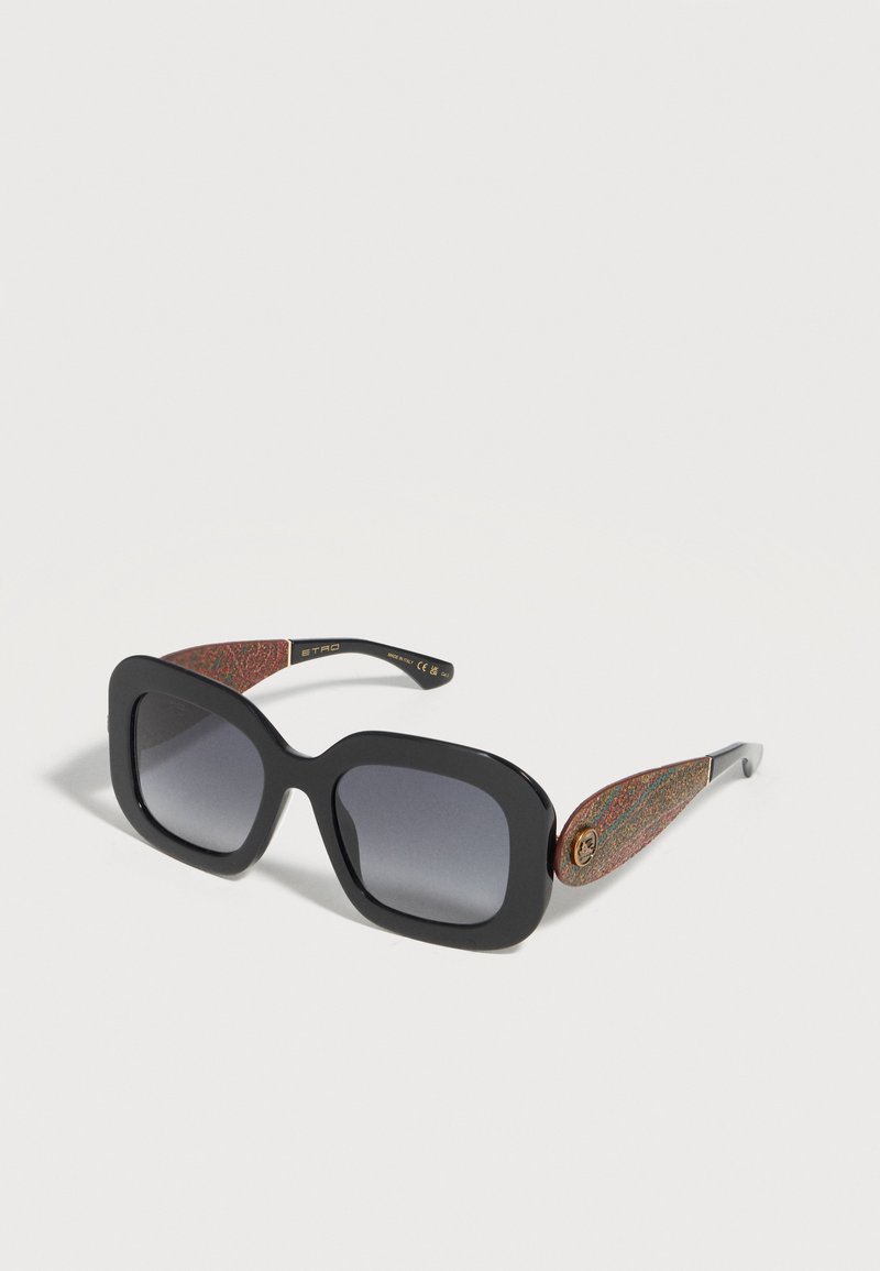 Lunettes de soleil carrées oversize noires avec verres dégradés foncés et branches multicolores texturées avec un petit logo rond doré.