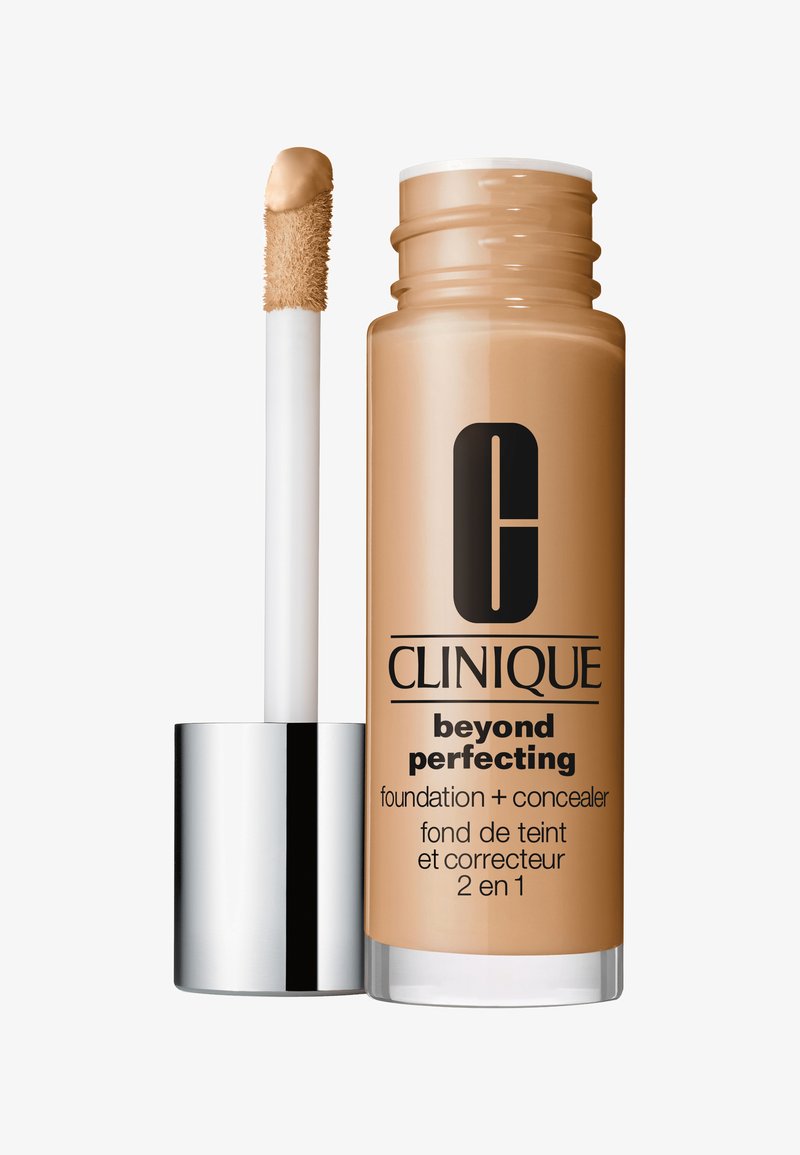 Fondotinta e correttore Clinique Beyond Perfecting in bottiglia di vetro, color tan, con applicatore bianco e cappuccio con accento argentato.