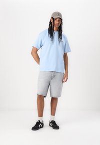 Lys blå kortærmet T-shirt, grå denim shorts, sorte sneakers med hvide striber og en grå kasket; afslappet pasform og moderne design.