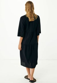 Svart klänning med trekvartslånga ärmar, med en lagerdesign och ögla-detaljer vid fållen. Slät tyg och avslappnad passform.