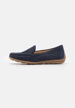 Marineblå ruskindsloafer med rund tå, synlig syning og brun gummisål. Har et slip-on design uden snørebånd.