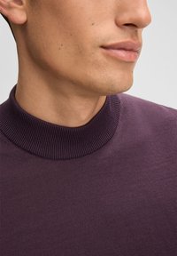 Dunkellila Rollkragensweater mit geripptem Kragen, glatter Textur und Nahaufnahme des Kragens und Halsbereichs.