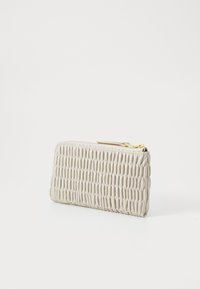 Beige lærpung med en teksturert, ribbet design og en glitrende gullfarget glidelås. Slank form, egnet for oppbevaring av kort og kontanter.