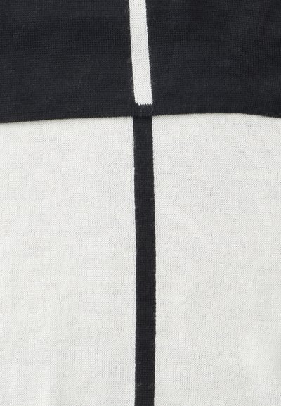 Gros plan d’un tissu tricoté noir et blanc avec des lignes noires verticales et horizontales formant un motif en croix.