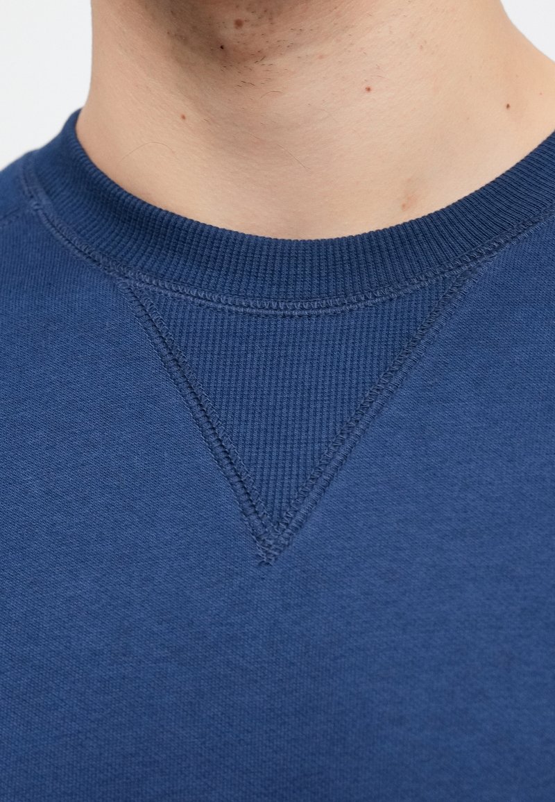 Crewneck-sweatshirt i mørkeblå bomuld med tekstureret halsudskæring og en trekantsyningsdetalje ved kraveområdet. Glat finish.