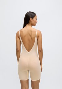 Bēšs bodijs ar zemu V-veida muguras izgriezumu, izgatavots no gludas, elastīgas auduma, kas stiepjas līdz vidusšķērslielumam. Plānas regulējamas lencītes.