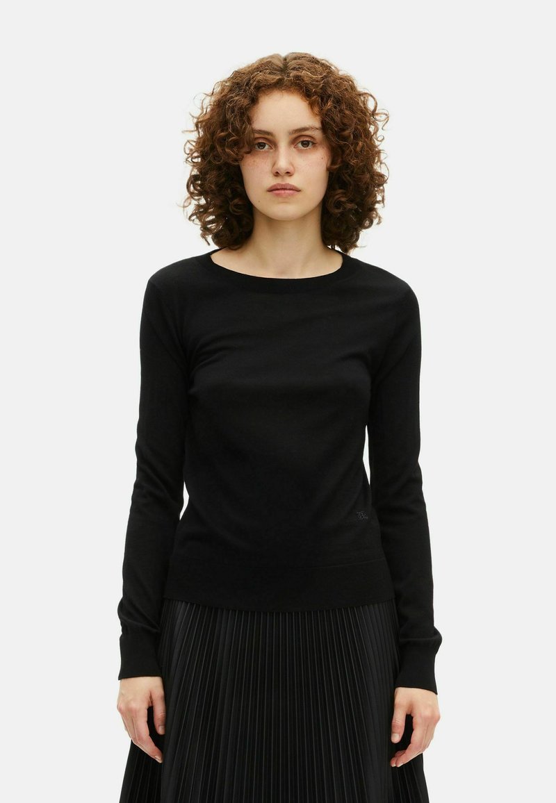 Maglione nero a maniche lunghe in tessuto morbido con scollo rotondo. Presenta una silhouette aderente e polsini e orlo leggermente a coste.