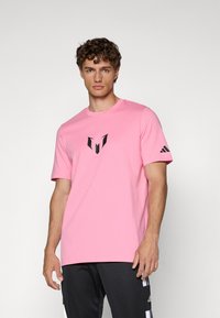 Pink cotton t-shirt with a crew neck and short sleeves. Features a black logo on the chest and an Adidas accent on the sleeve.