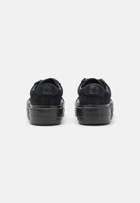 Sneakers negri din suede cu o finisare texturată, având o talpă groasă din cauciuc negru și un detaliu cu logo-ul stelei pe spate.