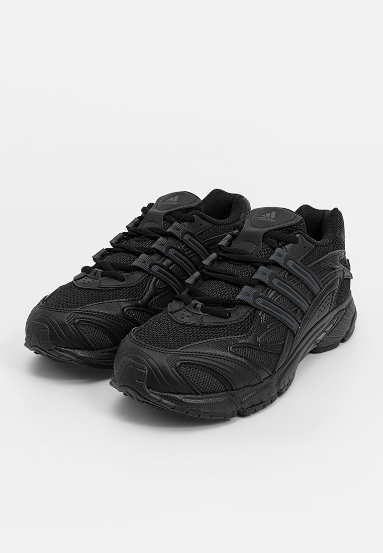 Par de zapatillas de running negras de Adidas con parte superior de malla y sintético, suelas gruesas y el diseño de las tres franjas características en los lados.