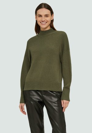 Olijfgroen trui met een hoge hals en verlaagde schouders, met een geribbelde zoom en manchetten, gedragen met zwarte leren broek.