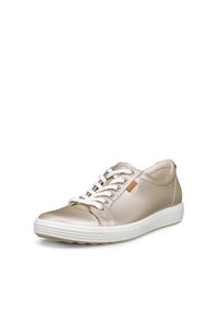 Baskets en cuir beige clair avec des lacets blancs et une semelle blanche épaisse, avec une petite étiquette logo marron sur le côté.