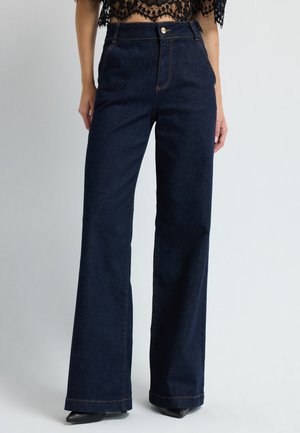 Dunkelblaue Denim-Hosen mit weitem Bein und hoher Taille, goldener Knopfverschluss und auffälliger Naht. Glatte Textur und ausgestellte Beinoptik.