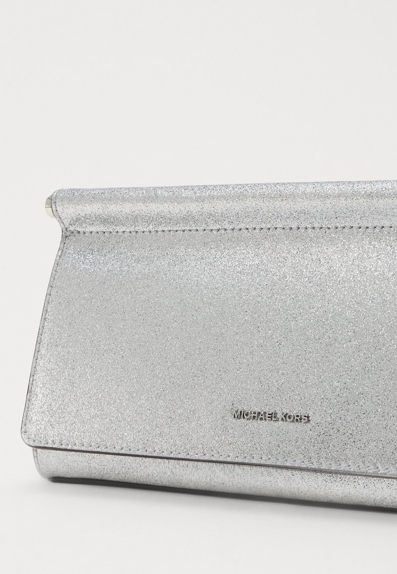 Borsa a pochette argento con finitura glitterata, forma rettangolare e chiusura a patta. Presenta il logo "MICHAEL KORS" impresso. Texture liscia.