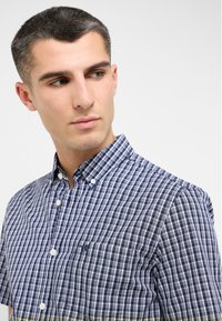 Koszula krótko rękawowa zapinana na guziki w granatowo-białą kratę, z kołnierzykiem typu button-down i jedną kieszenią na piersi. Gładki bawełniany materiał.