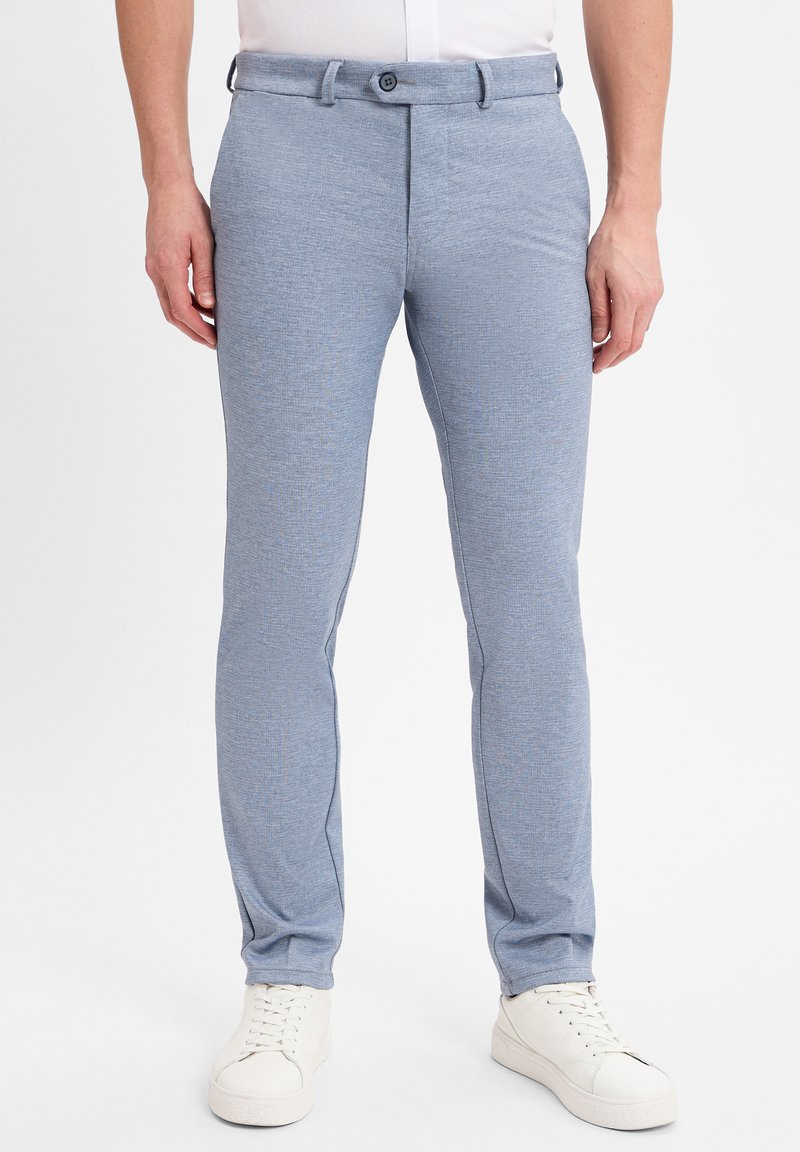 Lichtblauwe, slim-fit broeken gemaakt van gestructureerde stof met een subtiel patroon. Voorzien van een knoopsluiting en zijzakken. Draagt met witte sneakers.