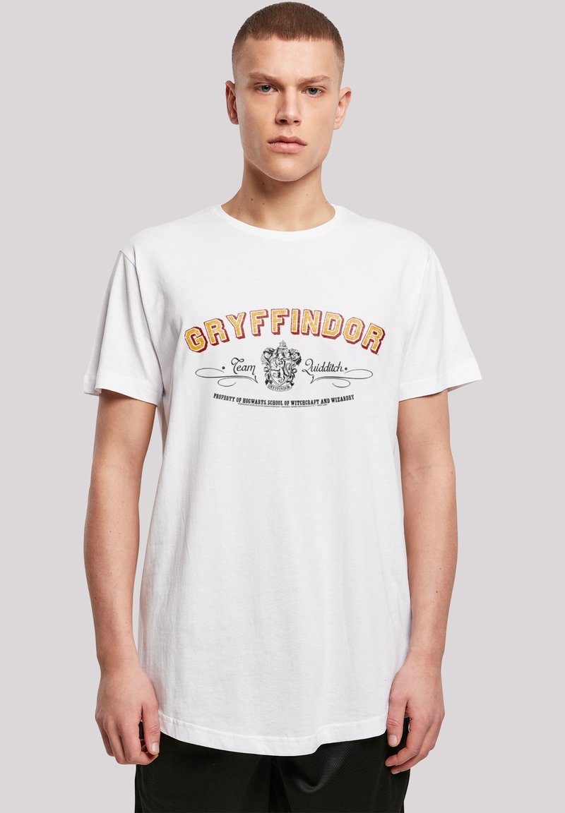 Hvit bomulls-T-skjorte med rød og gul "Gryffindor" tekst og et løveemblem, samt ekstra tekst i en vintage skrifttype. Vanlig passform, rund hals.