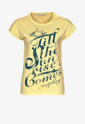 Żółta bawełniana koszulka z krótkimi rękawami, na której znajduje się niebieski graficzny napis wraz z symbolem słońca i słowem "replay".