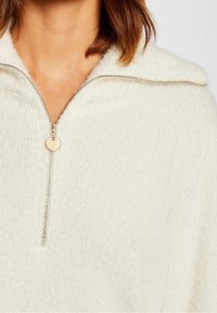 Kerma, muhkea vetoketjullinen neulepaita, jossa on leveä kaulus, hopeavetoketju ja pyöreä vetotappi. Pehmeä tekstuuri, jossa on riipputekstuuri.