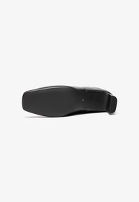 Μαύρο παπούτσι με λείο δερμάτινο επάνω μέρος, τετράγωνη μύτη και επίπεδη καουτσούκ σόλα. Μέγεθος 40 σημειωμένο στο κάτω μέρος. Μιν�ιμαλιστικός σχεδιασμός.