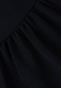 Tessuto nero con un design arricciato e una consistenza morbida, che mostra una leggera lucentezza e un colore uniforme su tutta la superficie.