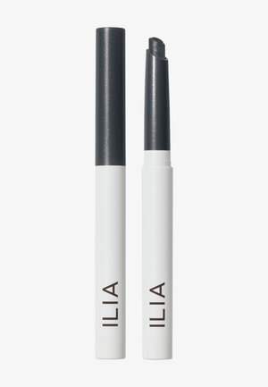Deux crayons de maquillage blancs et noirs portant l’inscription ILIA, l’un fermé et l’autre avec le produit noir sorti pour application.
