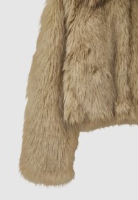 Beige Kunstpelzjacke mit plüschiger Textur, die ein kurzes Design und breite Ärmel aufweist. Der Stoff ist flauschig mit unterschiedlichen Längen.