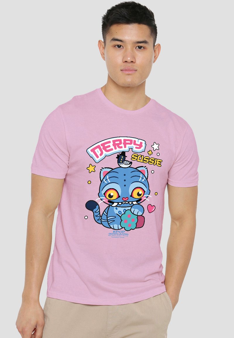 Young man wearing a pink shirt with a colorful cartoon blue cat holding a flower and the text "Derpy Sussie" on it.