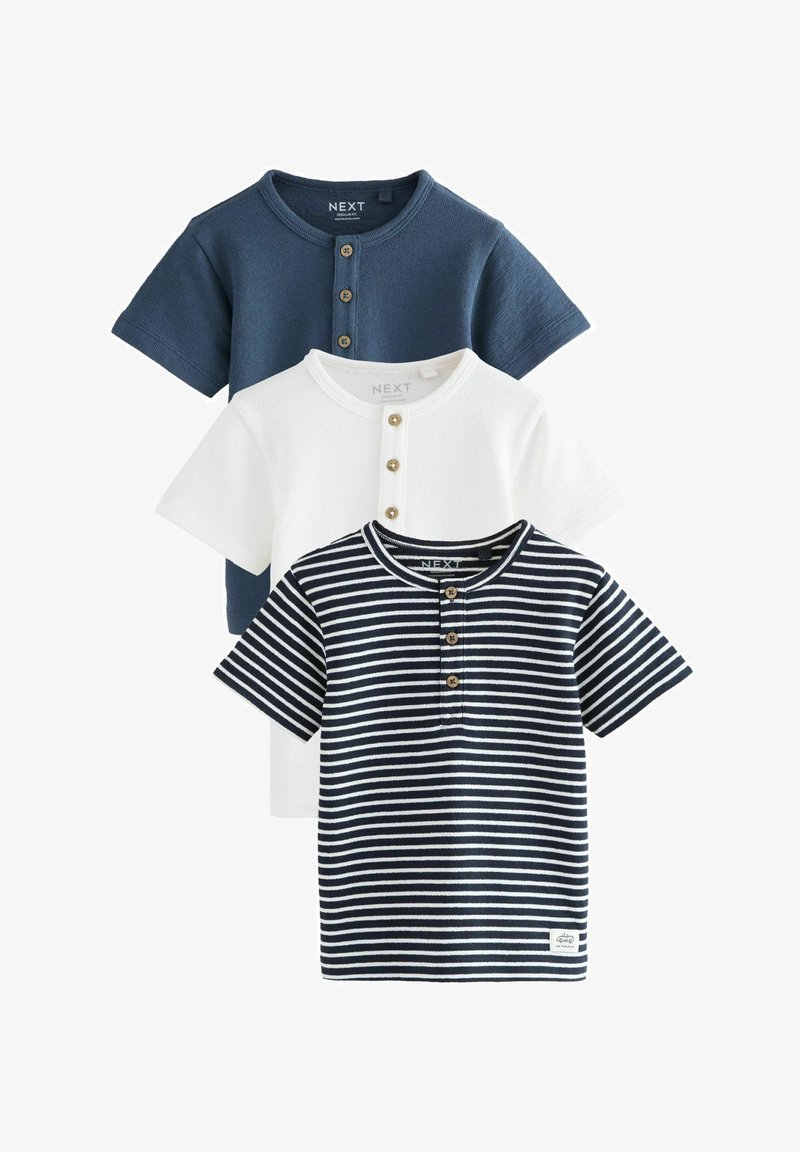 Tre magliette a maniche corte per bambini piccoli, una blu navy tinta unita, una bianca tinta unita e una a righe blu navy e bianche, ciascuna con patta frontale con bottoni.