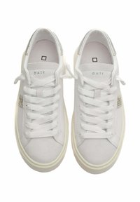 Zapatillas blancas con parte superior de cuero liso y gamuza, cordones planos, acentos metálicos plateados en el talón y suela de goma beige.