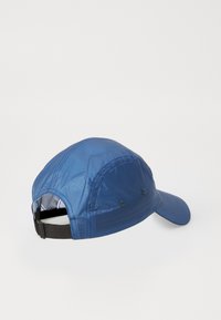 Blue cap made of lightweight, textured fabric. Features adjustable strap at the back, curved brim, and two ventilation eyelets on sides.