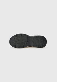 Semelle de chaussure en caoutchouc noir avec un motif de semelle texturé, un renflement central pour la flexibilité et des bords arrondis. Conçue pour l'adhérence et la stabilité.