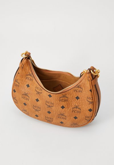 Sac à main en cuir marron en forme de croissant avec une fermeture éclair dorée et un motif en logo MCM noir, comportant des attaches de bague en métal doré.
