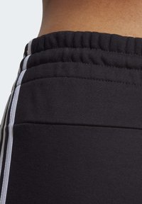 Svarta träningshorts med en elastisk midja, sidostråk i vitt och en mjuk textilfinish.