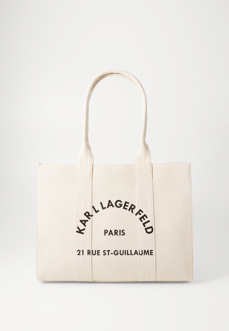 Canvas toteväska i krämfärg, med svart text: "KARL LAGERFELD PARIS 21 RUE ST-GUILLAUME." Dubbel robusta handtag för enkel bärning.