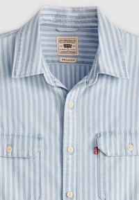 Camicia a maniche corte a righe blu chiaro con strisce bianche, colletto button-down, due tasche sul petto e etichetta Levi's con la scritta 'Relaxed'.