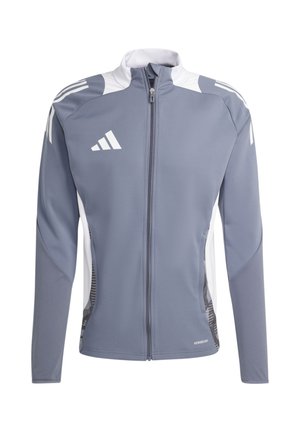 Giacca sportiva grigia con colletto alto, zip completa, dettagli bianchi e pannelli laterali texturizzati. Presenta tre strisce diagonali bianche sulle maniche.