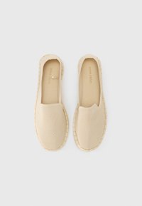 Beige instapschoenen van ademend mesh met een gestructureerd oppervlak en geweven details op de zool. Heeft een ontwerp met een ronde neus.
