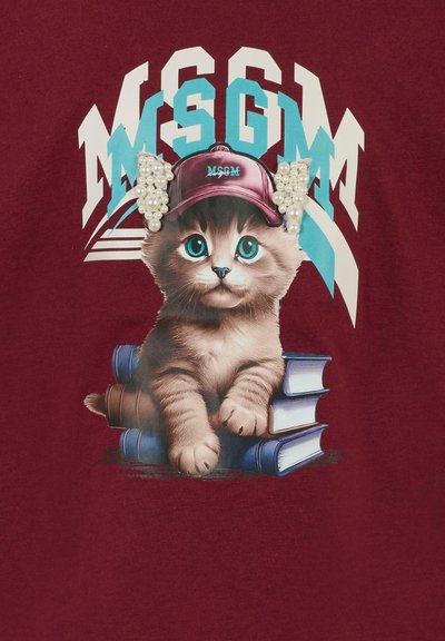T-shirt bordeaux con una grafica di un gattino con grandi occhi azzurri che indossa un cappellino con perle, seduto su libri impilati.