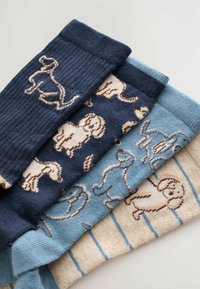 Fyra par strumpor med hundmotiv; färgerna inkluderar marinblå, ljusblå och beige med varierande ljusblå och bruna accenter.