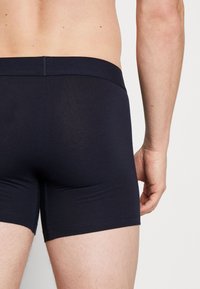 Donker marineblauwe katoen boxershorts met een gladde textuur, elastische tailleband en minimale stikdetails, met een slim fit ontwerp.
