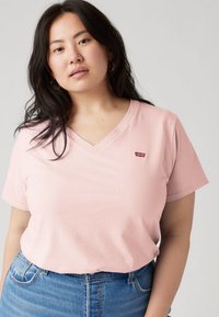 Ροζ βαμβακερό μπλουζάκι με λαιμόκοψη σε σχήμα V και κοντά μανίκια. Διαθέτει μικρό κόκκινο λογότυπο Levi's στο αριστερό στήθος.