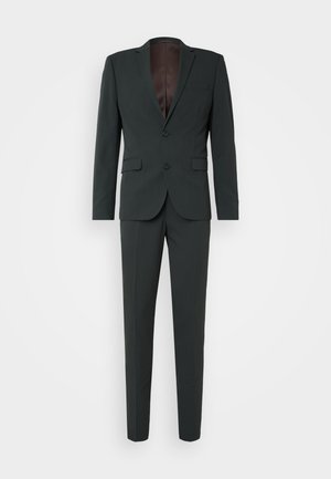 Mørkegrønn dress med en enkeltrad blazer, notched lapels, to knapper og smale bukser. Brun innerfôr, minimalistisk design.