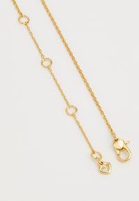 Zlato obarvana verižica z okroglimi povezavami, ki vsebuje srčkast obesek in karabinasto zaponko za zapenjanje. Površina je gladka.