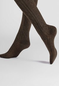 Braune knielange Socken mit strukturiertem Muster, die mit Rippungen und einer glatten Oberfläche versehen sind und über die Wade reichen.