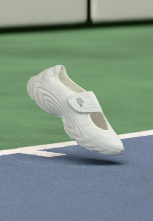 Scarpa sportiva bianca con design arrotondato, dotata di una fascia in Velcro, suola in gomma testurizzata e lati aperti per una migliore traspirabilità.